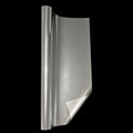 Roll of transparent glossy automotive window tint film partially unrolled against a solid black background, showcasing its smooth clear surface and reflective finish. Clear automotive tint film designed for custom vehicle styling.