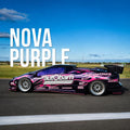 A low-profile sports car in a purple window tint and pink livery with 'autobarn' and 'RACEWORKS' branding, parked on an asphalt racetrack under a blue sky. Large white text overlay reads 'NOVA PURPLE'.