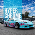 A turquoise sports car with hyperchrome tint window tint and pink. Purple flame decals, parked outdoors on asphalt under a blue sky. Large overlaid text reads 'HYPER CHROME' on a blue panel.