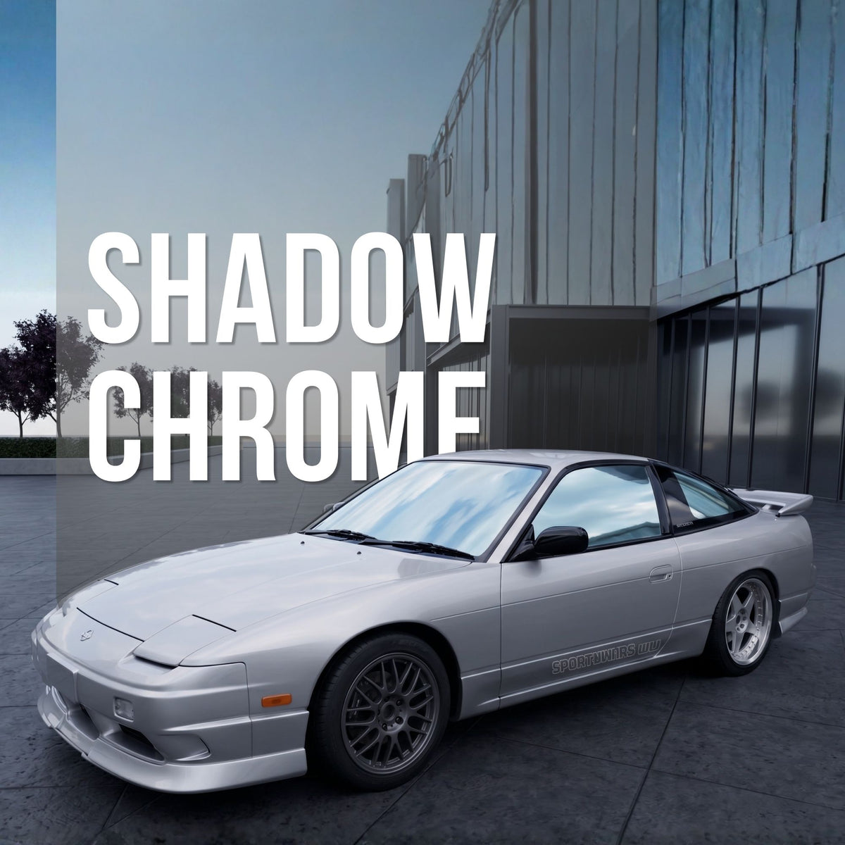 A silver sports coupe with a shadow chrome window tint parked outdoors in front of a modern building, with large overlaid text reading 'SHADOW CHROME'. The car has dark wheels and a glossy metallic finish.